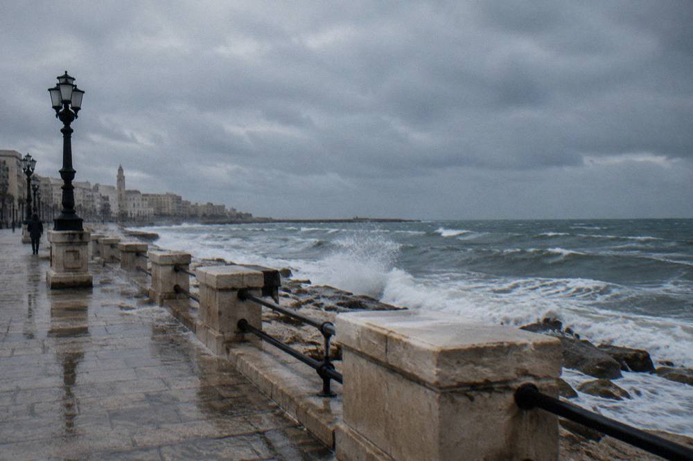 Grey winter sea with white-capped waves breaking against a seafront wall under a heavy sky