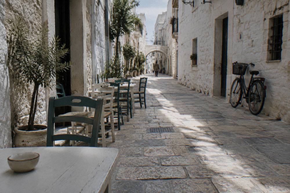 Whitewashed old town lane at midday with chairs and tables against the walls and stripes of sun and shadow