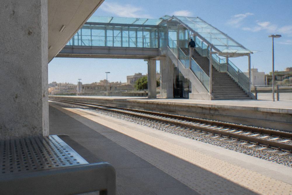 Station footbridge with stairs and a glass roof and a distant traveller with a rucksack