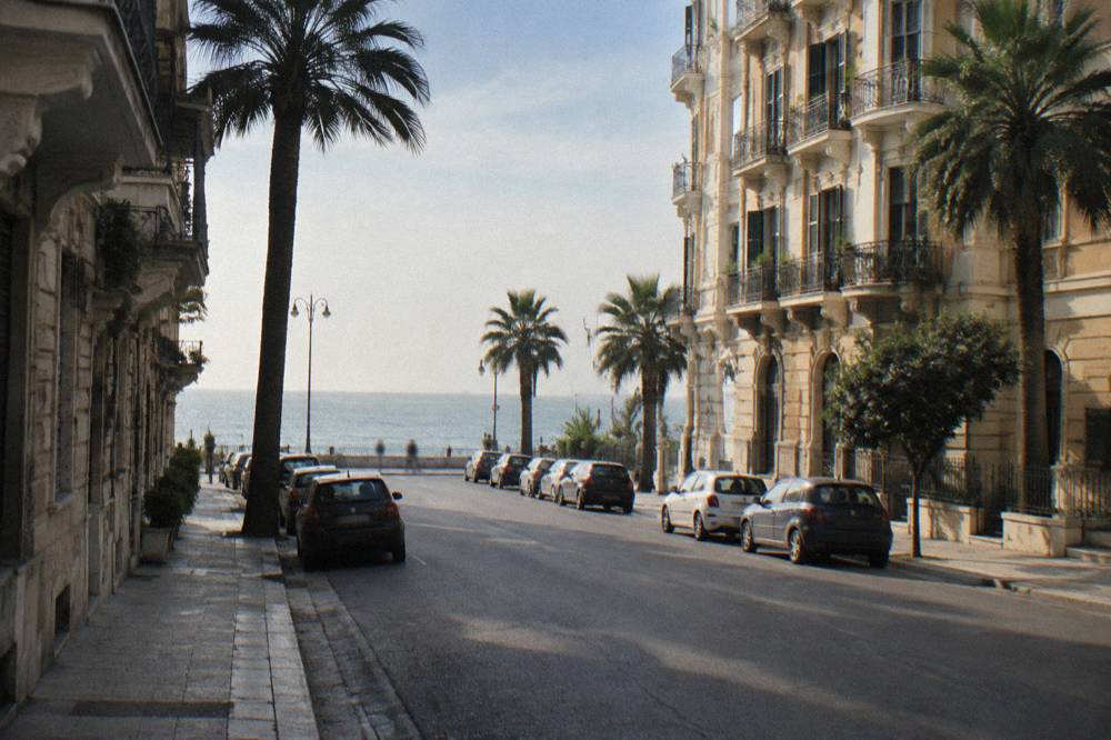Residential street of Liberty apartment buildings with iron balconies, palm trees and the sea at its end
