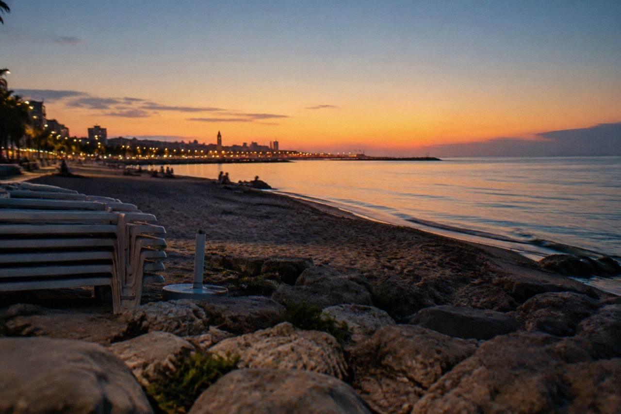 City beach in the evening with distant people on the sand, stacked sunbeds and an almost still sea