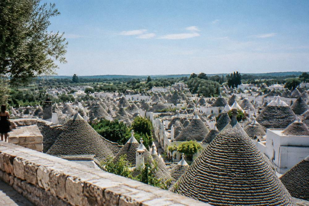 Wide view over a dense cluster of grey conical stone roofs from a raised belvedere