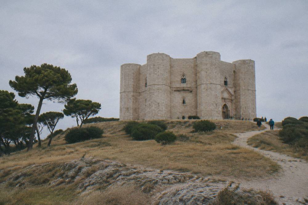 Octagonal pale limestone fortress with eight corner towers alone on a low hill above dry golden fields