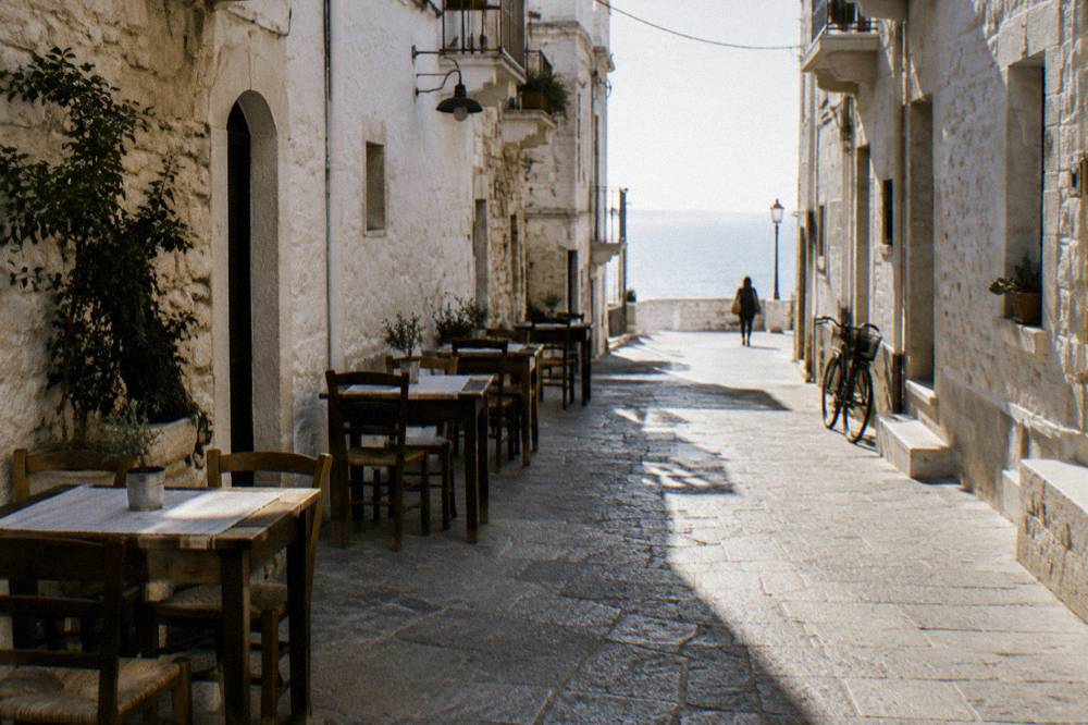 Whitewashed old town lane at midday with chairs and tables against the walls and stripes of sun and shadow