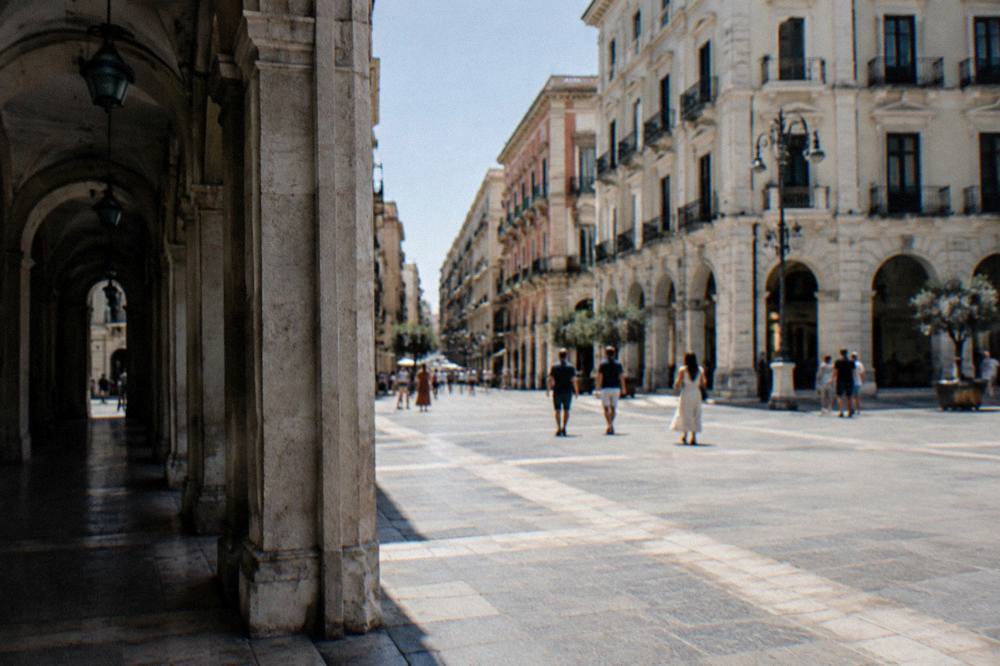 Shoppers far off crossing the paved intersection of a pedestrian street between tall facades
