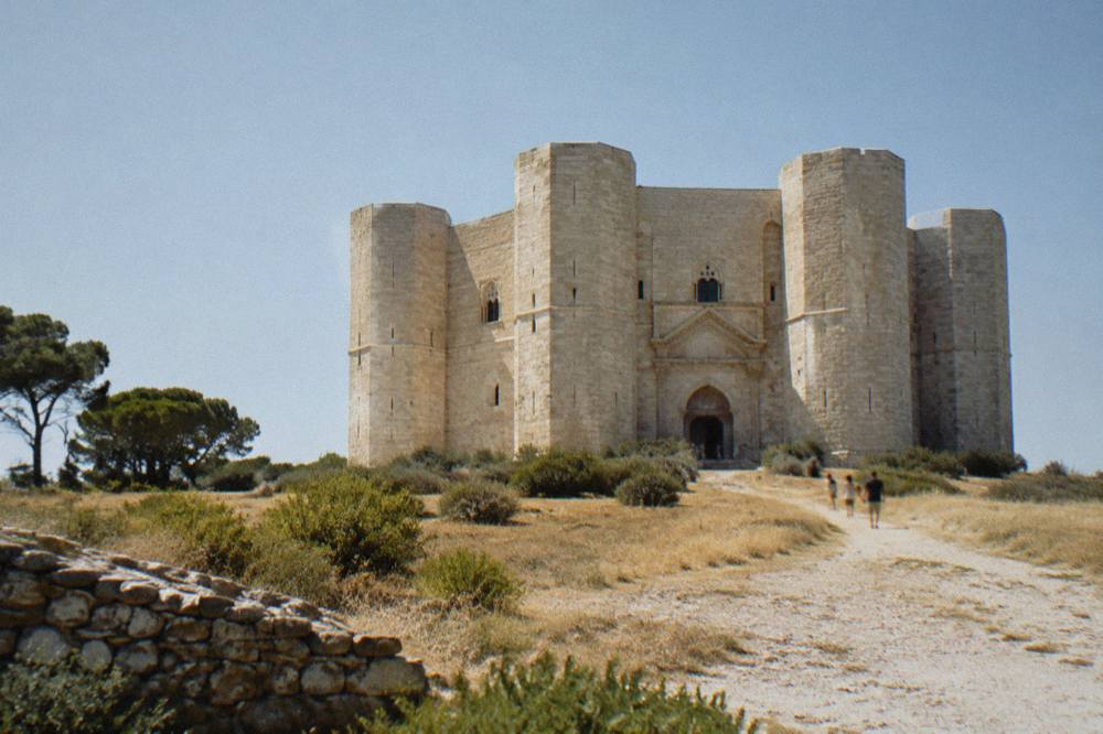 Octagonal pale limestone fortress with eight corner towers alone on a low hill above dry golden fields