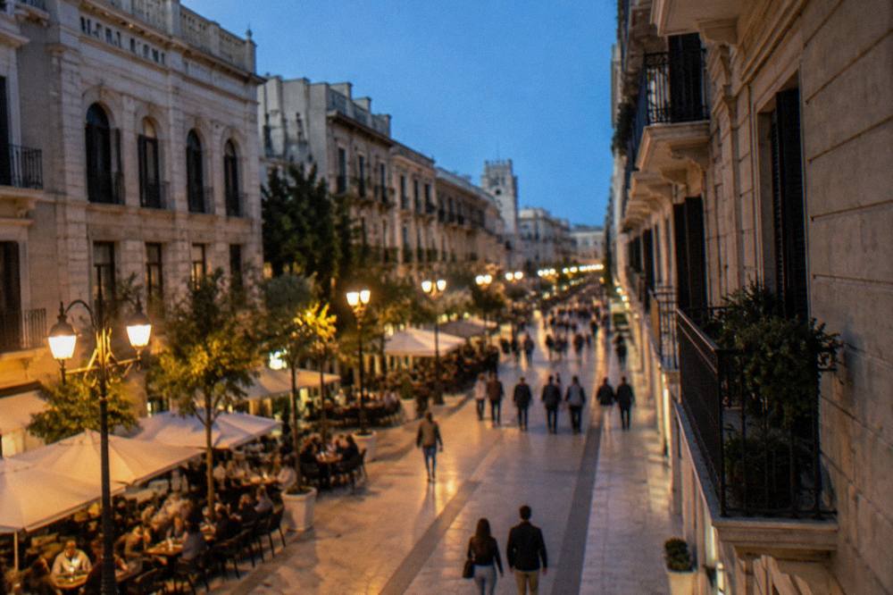 Pedestrian shopping street in the evening with lit lamps, cafe tables and out-of-focus people