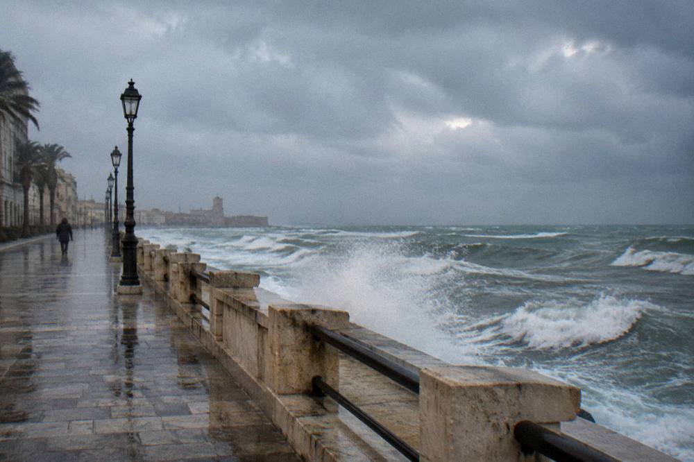 Grey winter sea with white-capped waves breaking against a seafront wall under a heavy sky